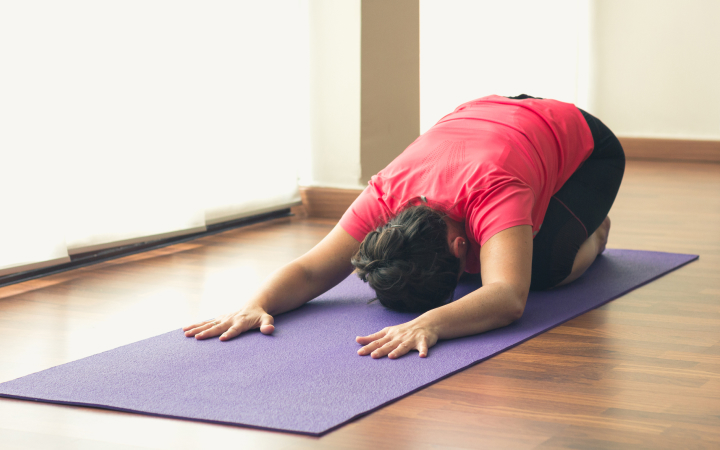 Eine Frau macht Yoga auf einer lila Matte.