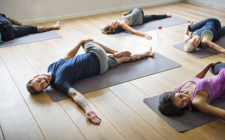 Frau beim Yoga üben in liegender Drehung zur Dehnung der Wirbelsäule auf der Matte