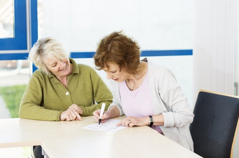 Analphabetin übt Schreiben mit Lehrerin