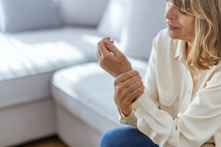 Frau mit CRPS (Morbus Sudeck) hält schmerzende Hand