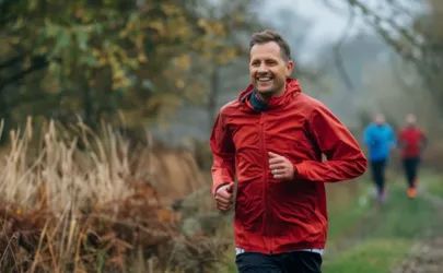 Lauftrainer läuft vor einer Gruppe auf einem Waldweg