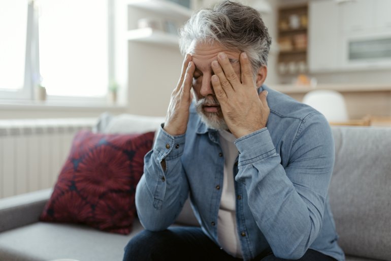 Mann mit Long-COVID reibt sich das Gesicht