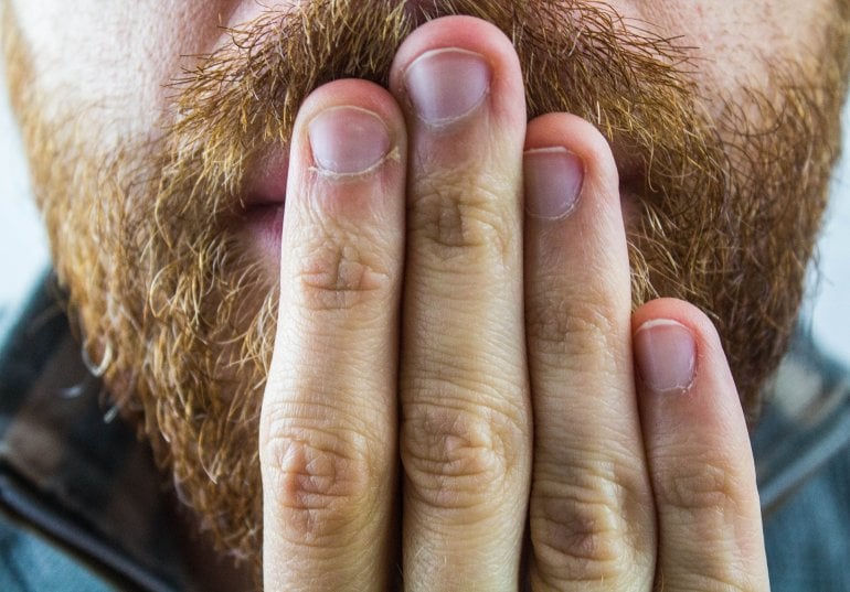 Mann mit Schluckauf hält Hand vor den Mund