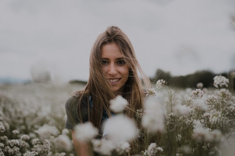 Frau zwischen Blumen: Blütenpollen belasten die Augen